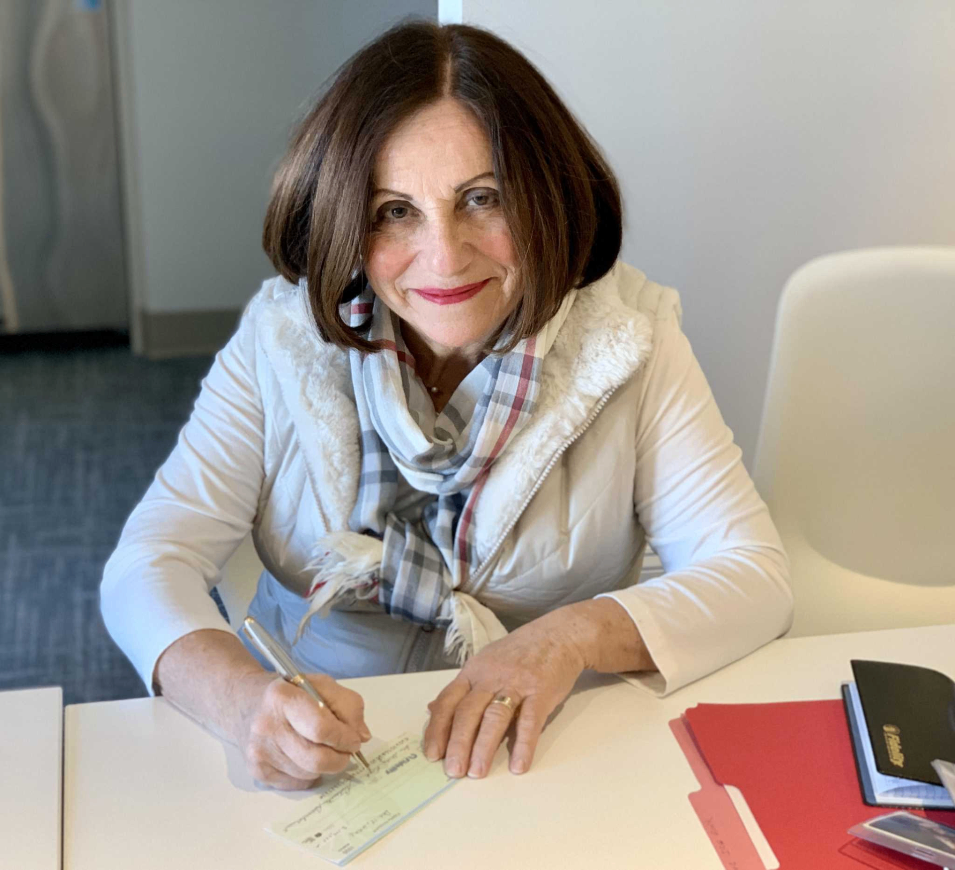 Toni Boucher seated at a desk, signing a document